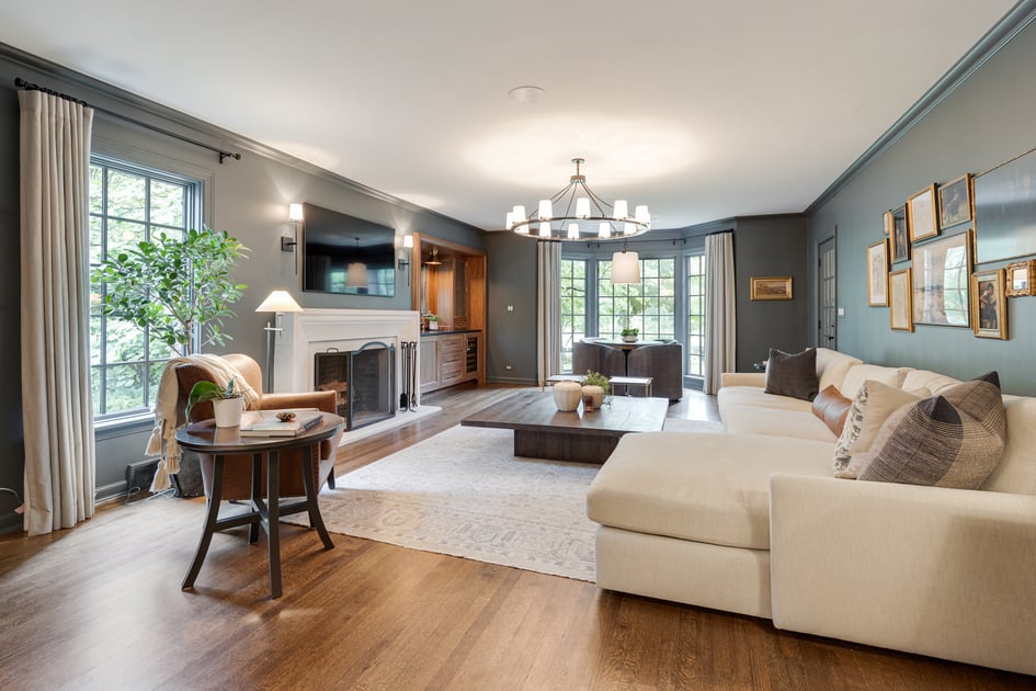 Picture of a spacious living room with a cream colored sectional couch sitting across from a stone fireplace and wall mounted TV