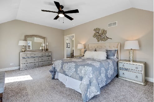 Master bedroom with light color accents and large windows that flood the room with natural light
