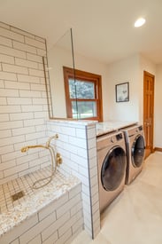 A wide angle shot of a newly remodeled mudroom with a side-by-side, front-loading washer and dryer.