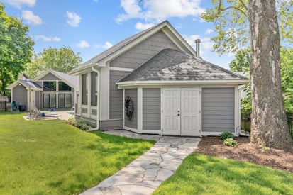 Shed with storage space in the back yard with a large tree beside the path