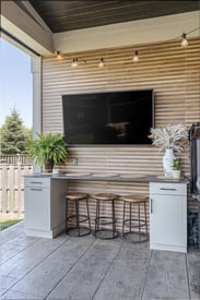 Wall mounted TV over a small outdoor seating area under the porch cover