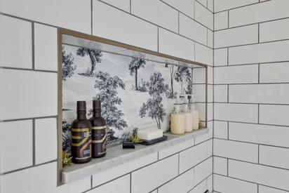 Built in shelf inside a shower with small white tile walls