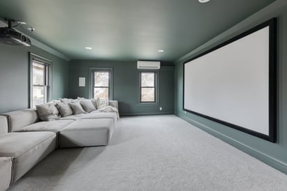 Basement theatre room with a modular sofa and a projector screen on the wall