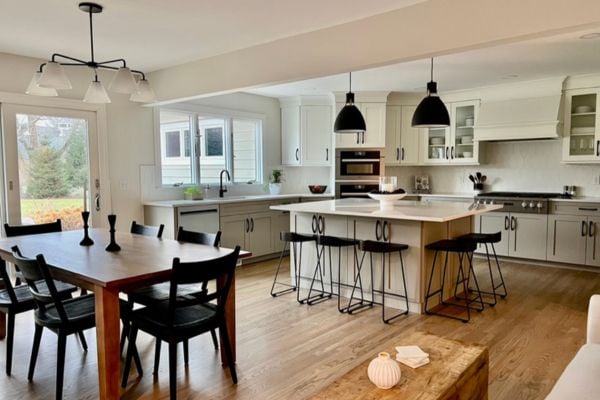 Open floor plan of a kitchen with black pendant lights over a luxurious kitchen countertop