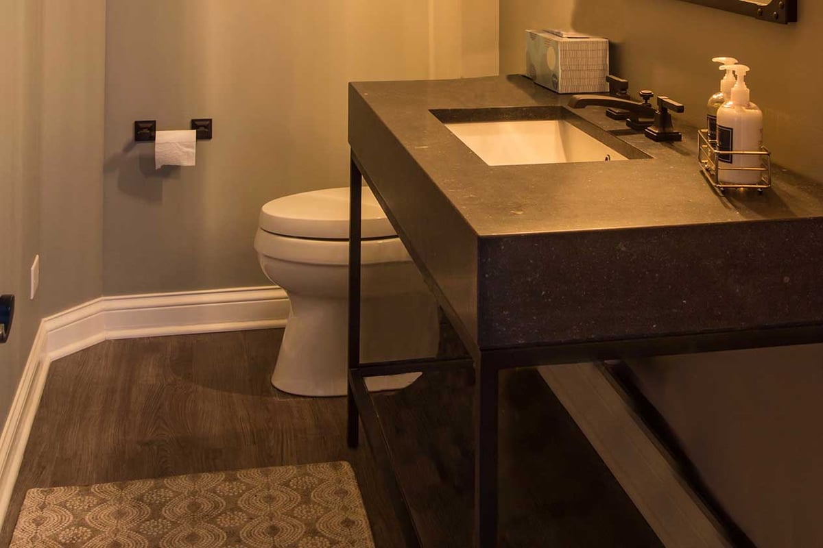 Dark granite bathroom vanity with luxury vinyl tile flooring