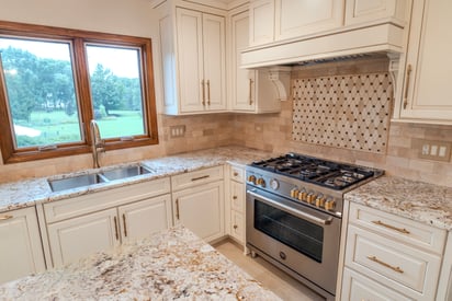 Side angle of a newly remodeled kitchen with white cabinetry, stainless steel over and range, with a small tile backsplash