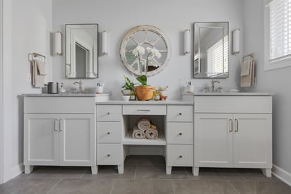 Front facing photo of a bathroom counter top with two separate vanities connected by a hutch with a countertop