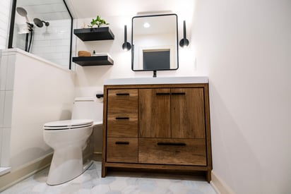 Low angle photo of the bathroom vanity with the toilet on the left and the shower visible in the upper left corner