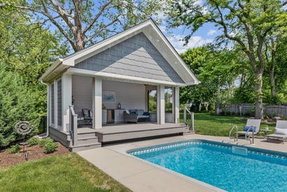 Exterior of a screened in pool house that overlooks a backyard swimming pool
