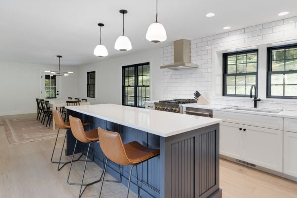 Contemporary kitchen with a pure white design, blue kitchen island with bar stool seating, and quartz countertops