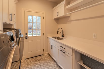 efficient and functional mudroom with a sink and side-by-die washer and dryer combo