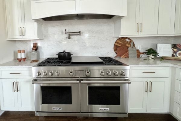Stainless steel dual oven with electric stovetop set into a granite countertop work space for cooking and baking