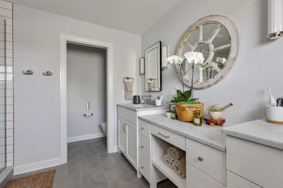 A bathroom with two vanities on the right side, a walk-in shower on the left, and a toilet with a sliding door