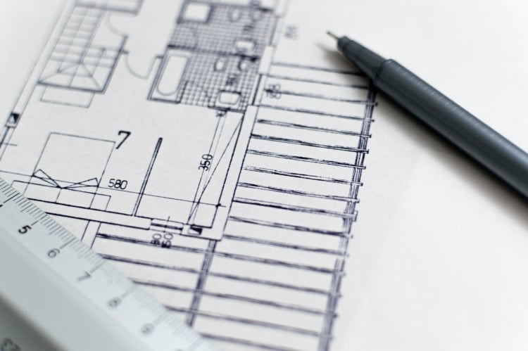 A picture of a home floorplan from an architect with a pen and a ruler laying on top of the paper