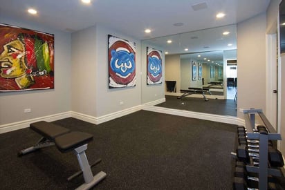 Full home gym with a mirror wall and dumbbell rack. There is also Chicago Blackhawks and Chicago Cubs artwork on the walls