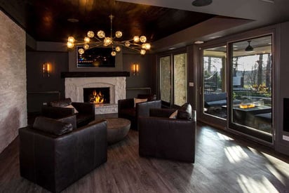 Basement with four leather arm chairs and a warm stone fireplace in the back