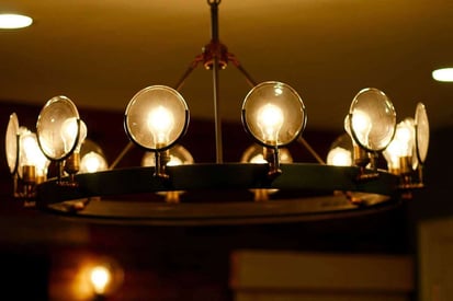 Close up of a basement chandelier with round lighbulbs lining the top of the frame