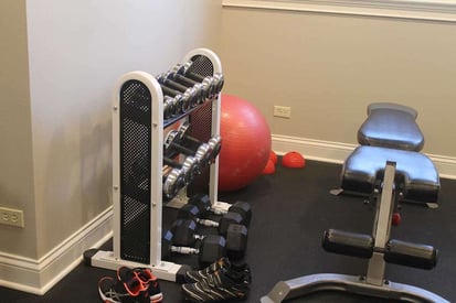 Home workout room with a set of dumbbells sitting on a rack and a bench