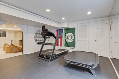 Home gym with a treadmill and trampoline with the American flag in the background