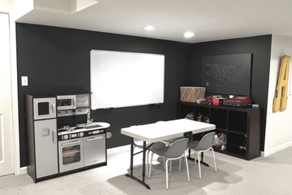 Basement brainstorming office with a white board, table, and two plastic chairs