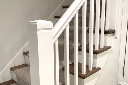 Banister next to the basement steps that is painted white