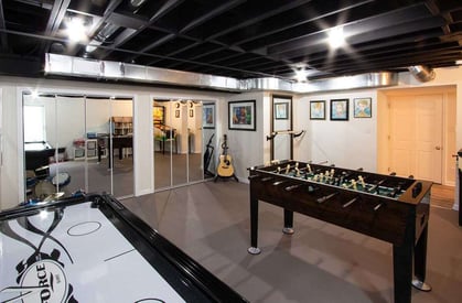 Different angle of a finished basement with a foosball table and an air hockey table