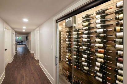 Basement hallway with a glass case showcasing lots of different bottles of wine