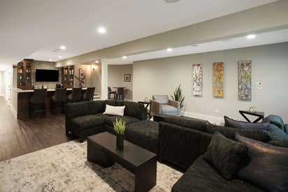 Open floor plan basement living room with an S-shaped sectional couch