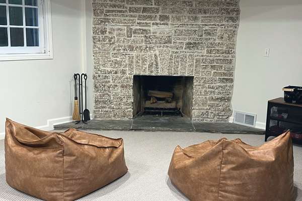 Basement family room area with a stone fireplace and two leather bean bag chairs