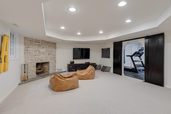 Basement family room with two leather bean bag chairs, a media center and a stone fireplace and a home gym