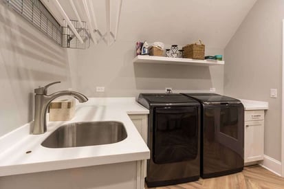 black washer and dryer that are both top load with a close up of a sink to the left of the countertop