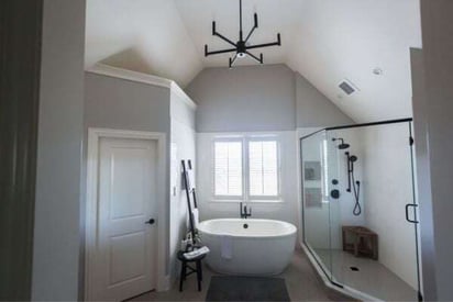 Modern bathroom with high cathedral ceilings and a modern chandelier hung from the center