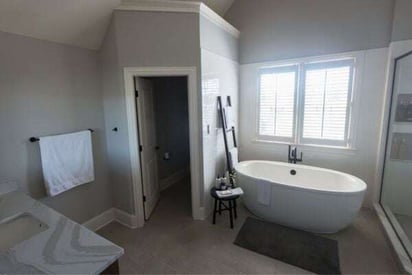 Wide angle view of a bathroom with a stand alone tub and a dedicated room for the toilet