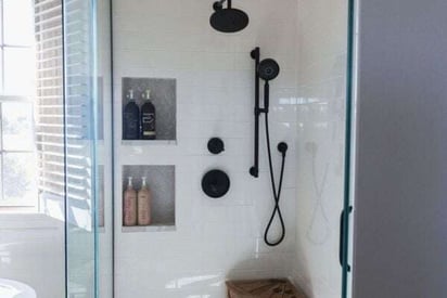 Walk in shower with embedded shelves and black fixtures for a sleek and modern look