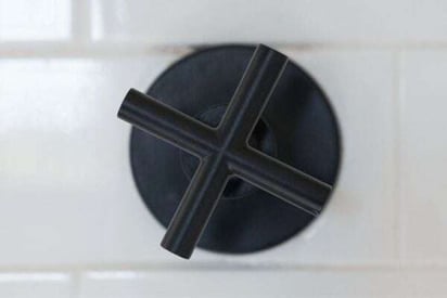 Close of view of a black shower handle with a cross shaped handle