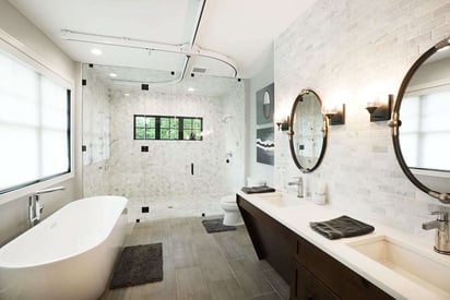 Wide angle of a high-end, expensive bathroom remodel with a double vanity on the right, a tub on the left, and an oversized walk-in shower on the far wall