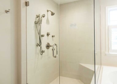 walk in shower with multiple shower heads and gold fixtures