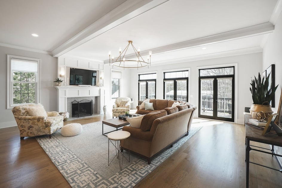 A classic and elegant fireplace nested within a sleek and stylish mable mantel and complemented by wooden cabinetry wall with a chandelier hanging from the ceiling