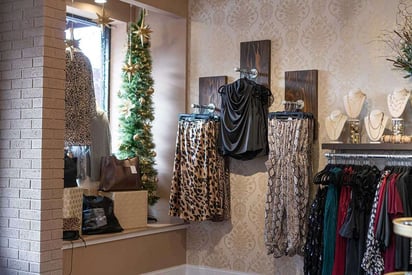 Designer clothing and dresses hung in a window display of a small shop