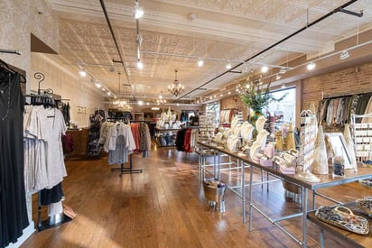 High ceiling clothing and boutique with lots of bags on display on a table