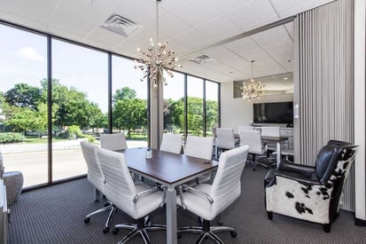 Elegant meeting room with white rolling chairs rolled up to a small rectangular wooden table