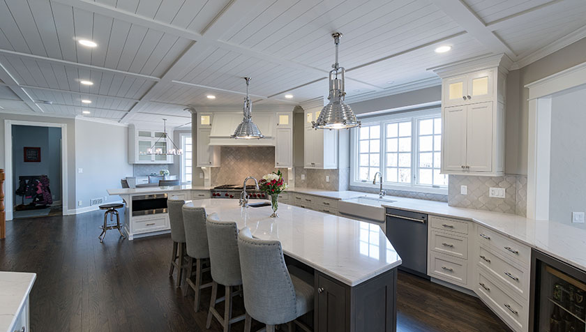 Luxurious kitchen remodel with white quartz counter top kitchen island with can lighting and overhead pendant lamps