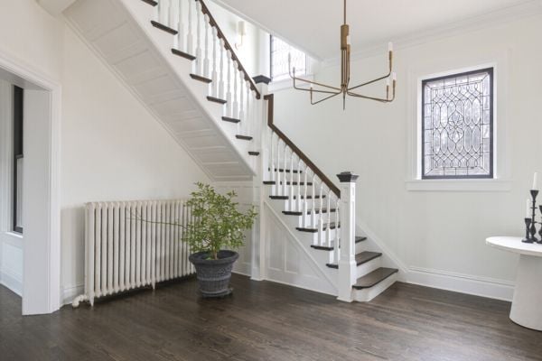 Front Entrance interior with bronze candelabra chandelier, dark wood floors, a clear stained glass window and a dark wood and white staircase