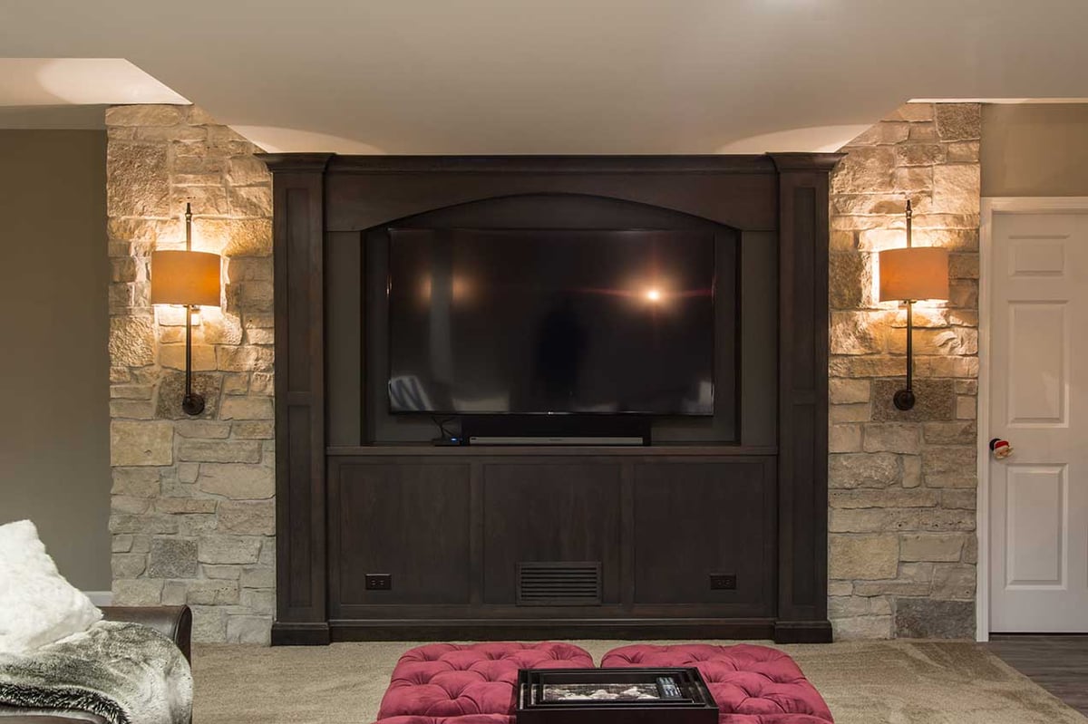 Luxury basement remodel with rich dark wood fireplace and stone