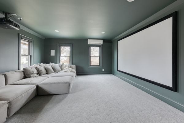 Home Theater_Media Room with sage green walls and light carpeting, featuring a large media screen and flexible sectional seating