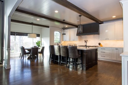 Kitchen with exposed rafters, pendant lights, and an island with four high-boy chairs for seating