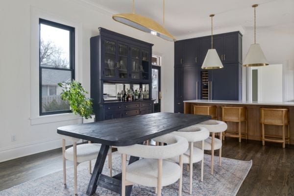Kitchen Dining Table with barrel armchairs and a linear gold pendant light, featuring navy blue cabinetry and hutch_bar, a natural wood island with large cone shaped white and gold pendant lights