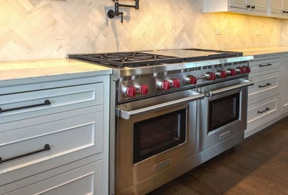 side by side double open and range with red knobs and a decorative tile backsplash