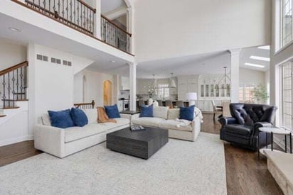 open and spacious family room with a white sectional couch, blue throw pillows, and very high ceilings