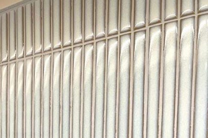 Close up of a silver tile backsplash with white grout in between the tiles